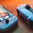 A gaming scenario featuring a smartphone with a game interface next to two controllers on a wooden surface. The smartphone displays vibrant images and icons, while the controllers feature a sleek, modern design with buttons and joysticks prominently visible. Warm lighting enhances the scene.